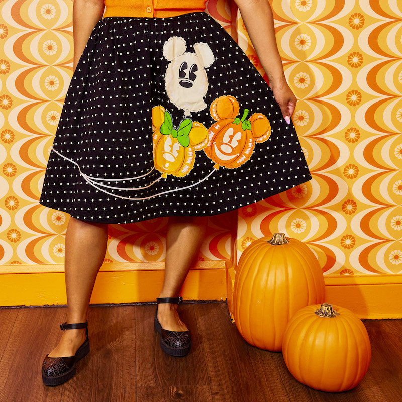 Woman wearing the Pumpkin Balloon Sandy Skirt, showing off the balloon designs on the skirt, standing next to pumpkins 
